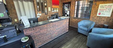 A reception area with a brick counter, a desk, a chair, and a bulletin board.