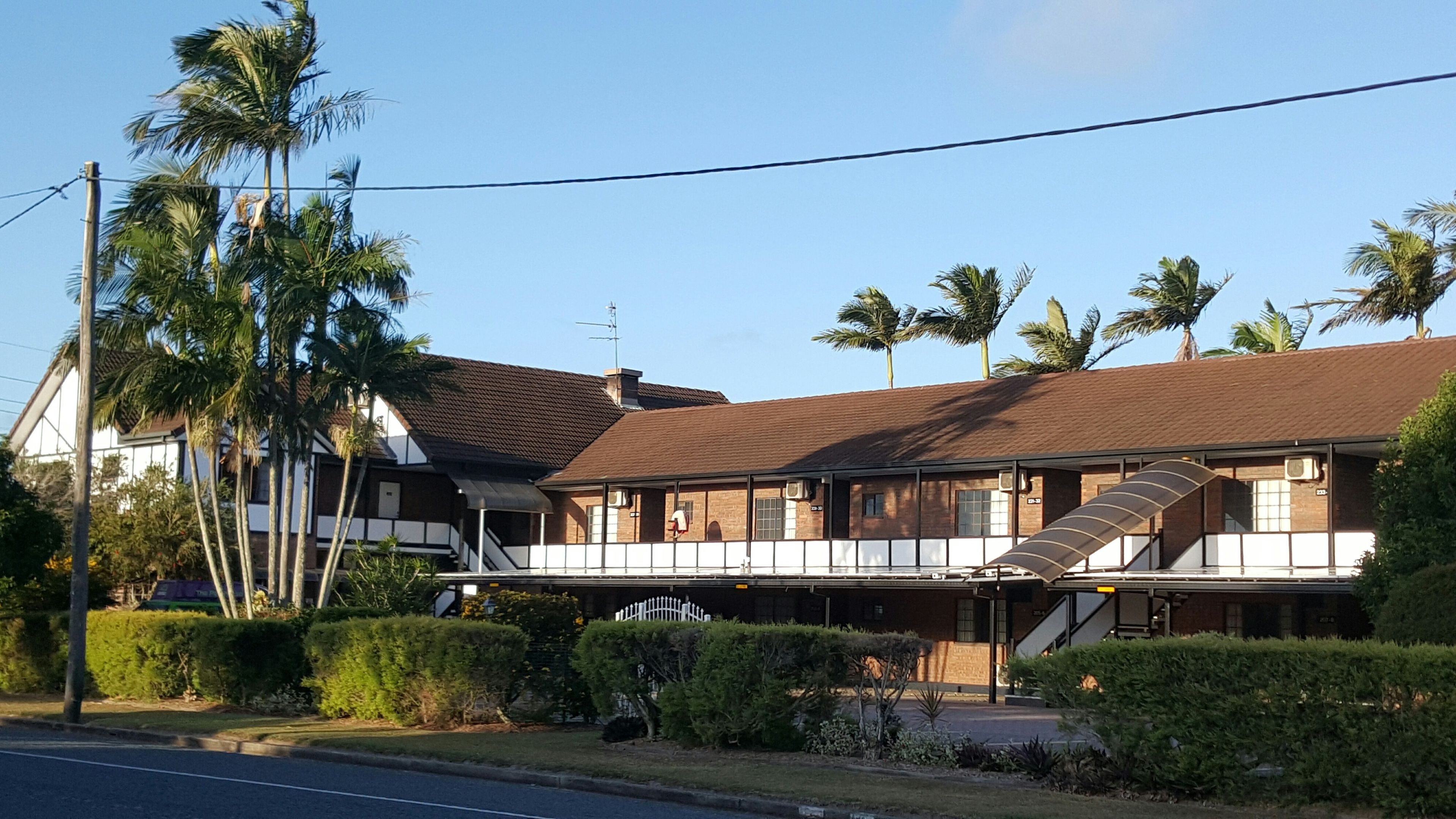 A two-story building with a flat roof, a balcony, and a staircase leading to the upper floor.