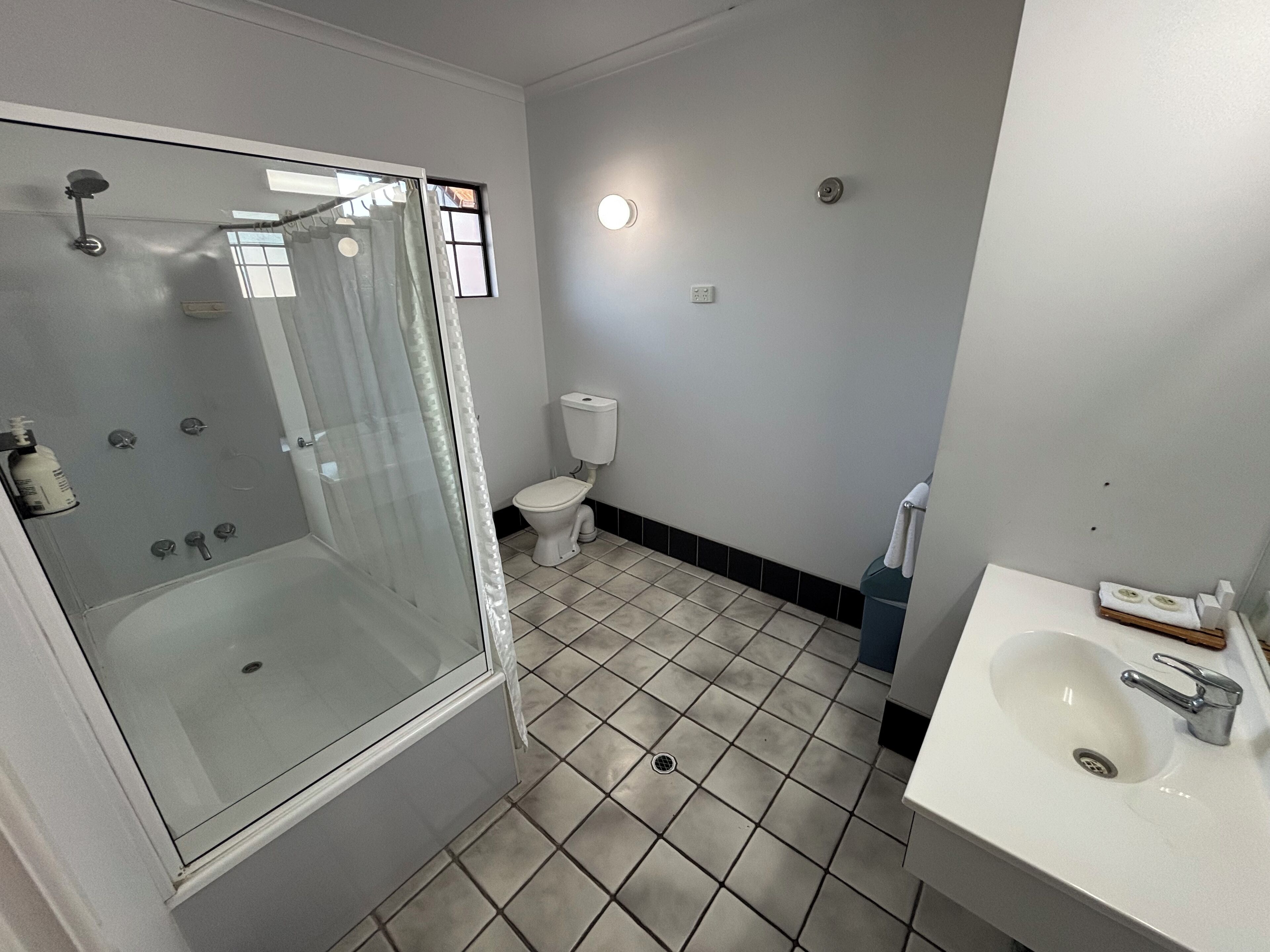A bathroom with a glass-enclosed shower, a toilet, and a sink with a mirror.
