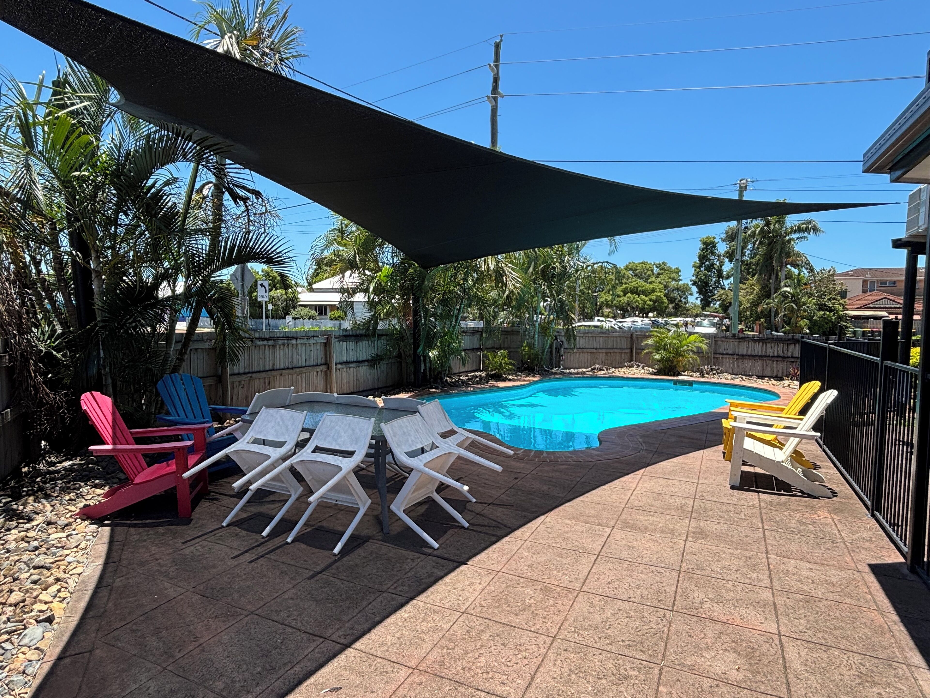 Um quintal com piscina, móveis de pátio e área coberta.