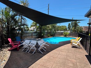 Una piscina al aire libre, sillones reclinables de piscina