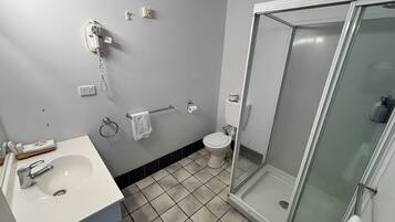 Un baño con lavamanos, inodoro y ducha con mampara de vidrio.