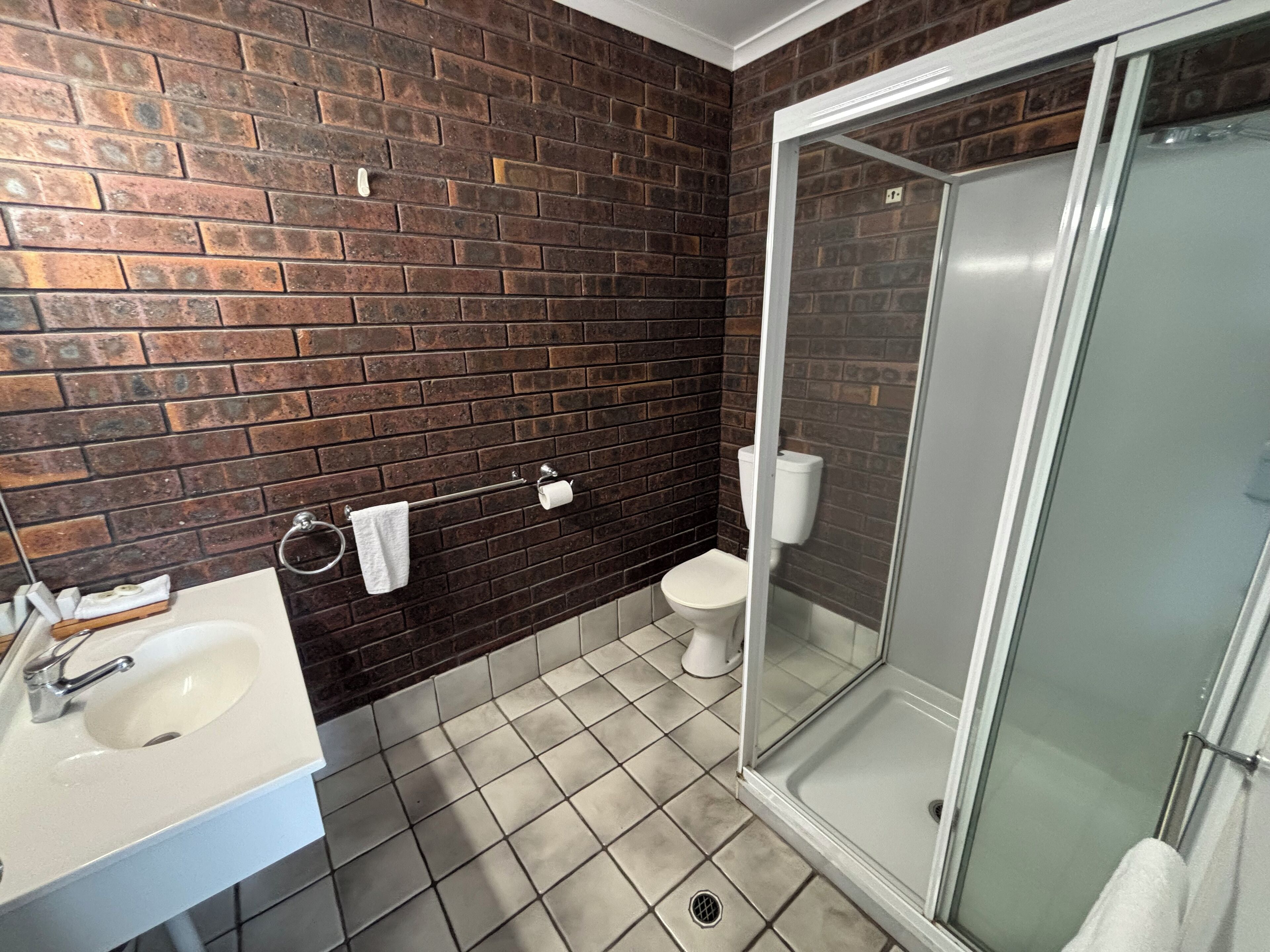 A bathroom with a white sink, a toilet, and a glass-enclosed shower.