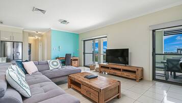 A modern living room with a grey sectional sofa, a wooden coffee table, and a TV on a wooden stand.