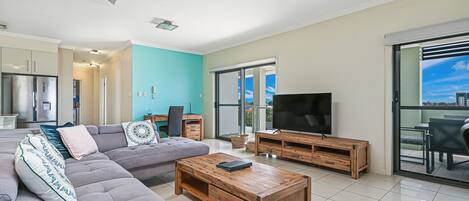 A modern living room with a grey sectional sofa, a wooden coffee table, and a TV on a wooden stand.