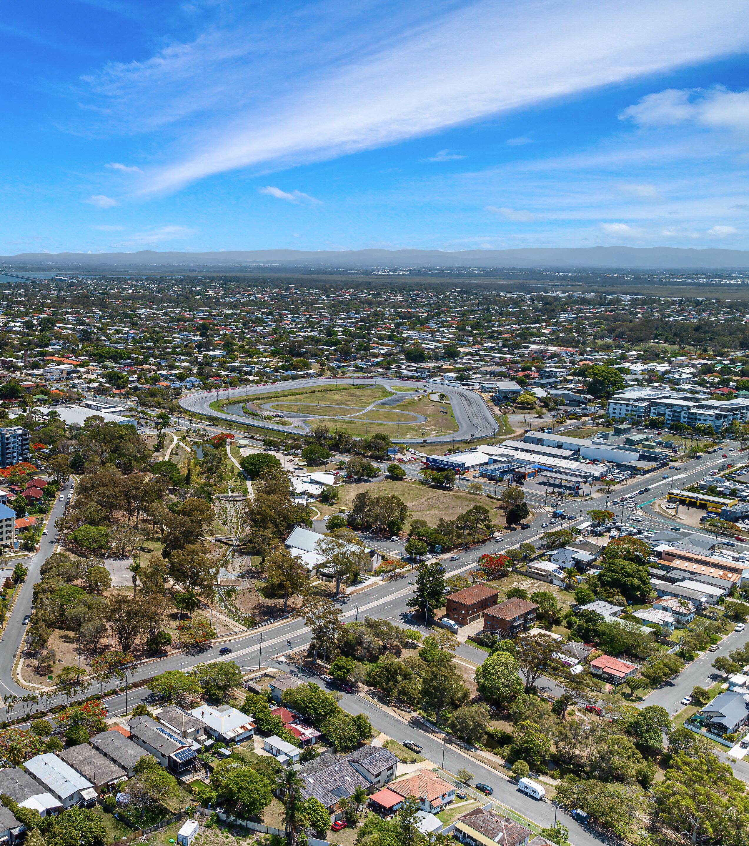 Vista aérea de una zona residencial con casas, calles y un espacio abierto grande con una pista.