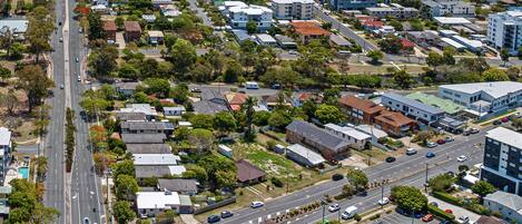 An aerial view of a residential area with multiple buildings, roads, and vehicles.