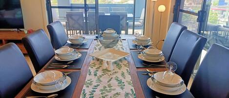 A dining table set for six with a view of the city through large windows.