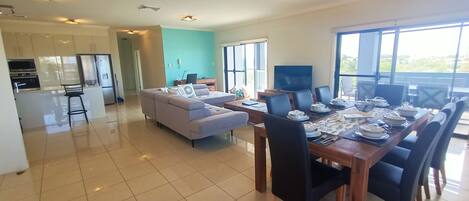 A spacious living area with a dining table set for six, a sofa, and a kitchen area with modern appliances.
