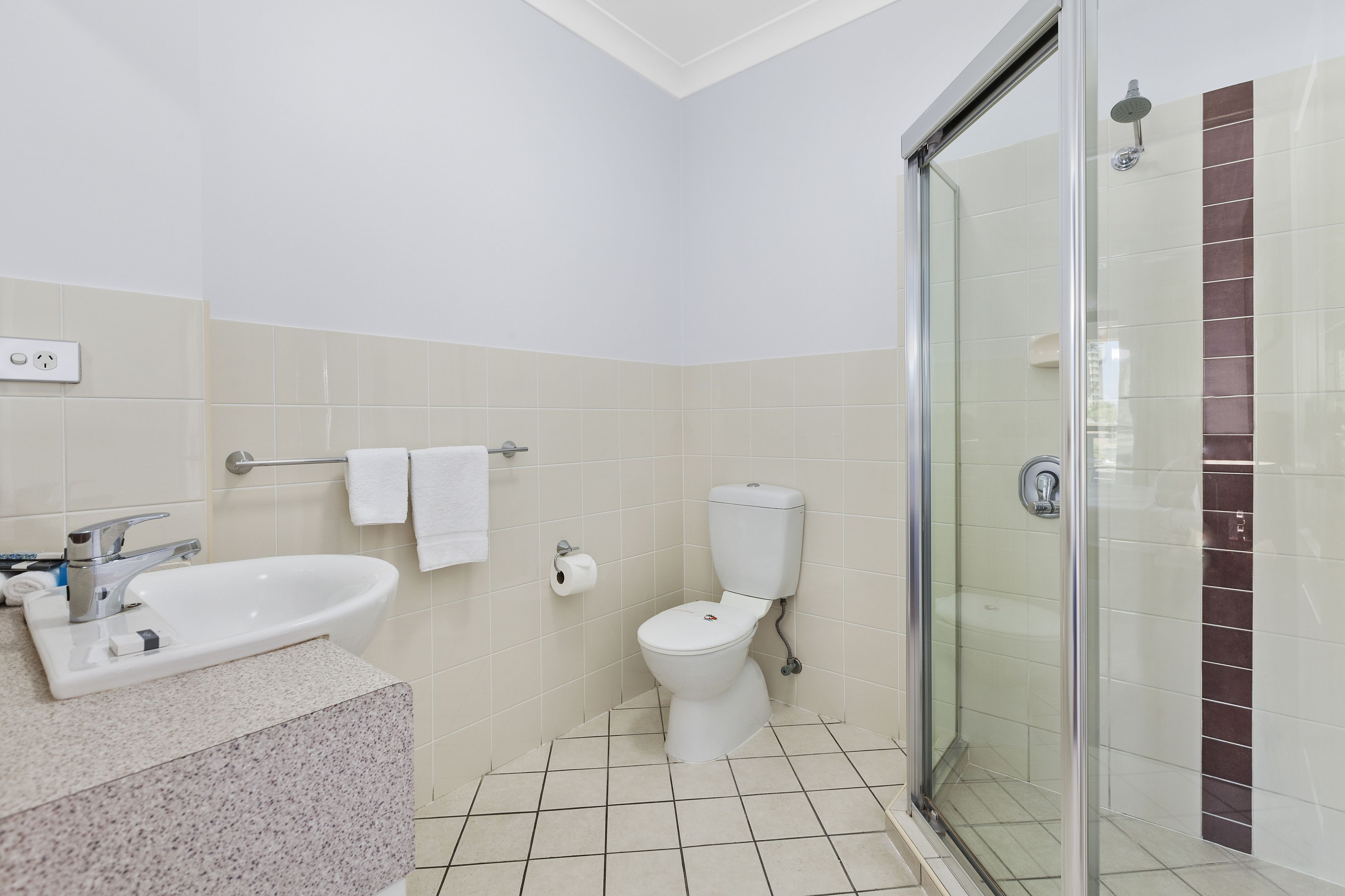 A bathroom with a sink, toilet, and glass shower enclosure.
