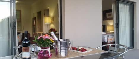 A glass table with a bottle, a metal bucket, and a vase with flowers.