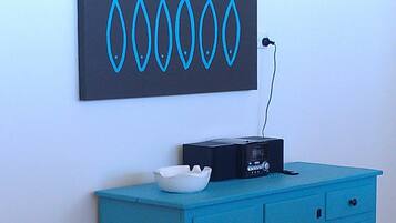 Un mueble azul con una radio negra y un cuenco blanco encima.