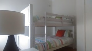 A bunk bed with a striped bedspread and a red pillow.