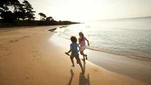 Two children running along a sandy beach with the ocean in the background. - NRMA Phillip Island Beachfront Holiday Park (Cowes)