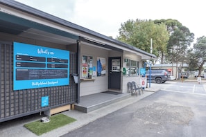 A building with a weather display, a sign for Phillip Island Beachfront, and a gas station sign. - NRMA Phillip Island Beachfront Holiday Park (Cowes)