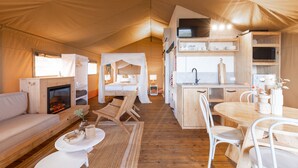 A cozy tented accommodation with a fireplace, a dining area, and a kitchenette. - NRMA Phillip Island Beachfront Holiday Park (Cowes)