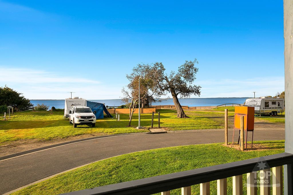 Un terrain de camping avec des emplacements pour camping-cars, un espace pour tentes et une vue sur l’eau.