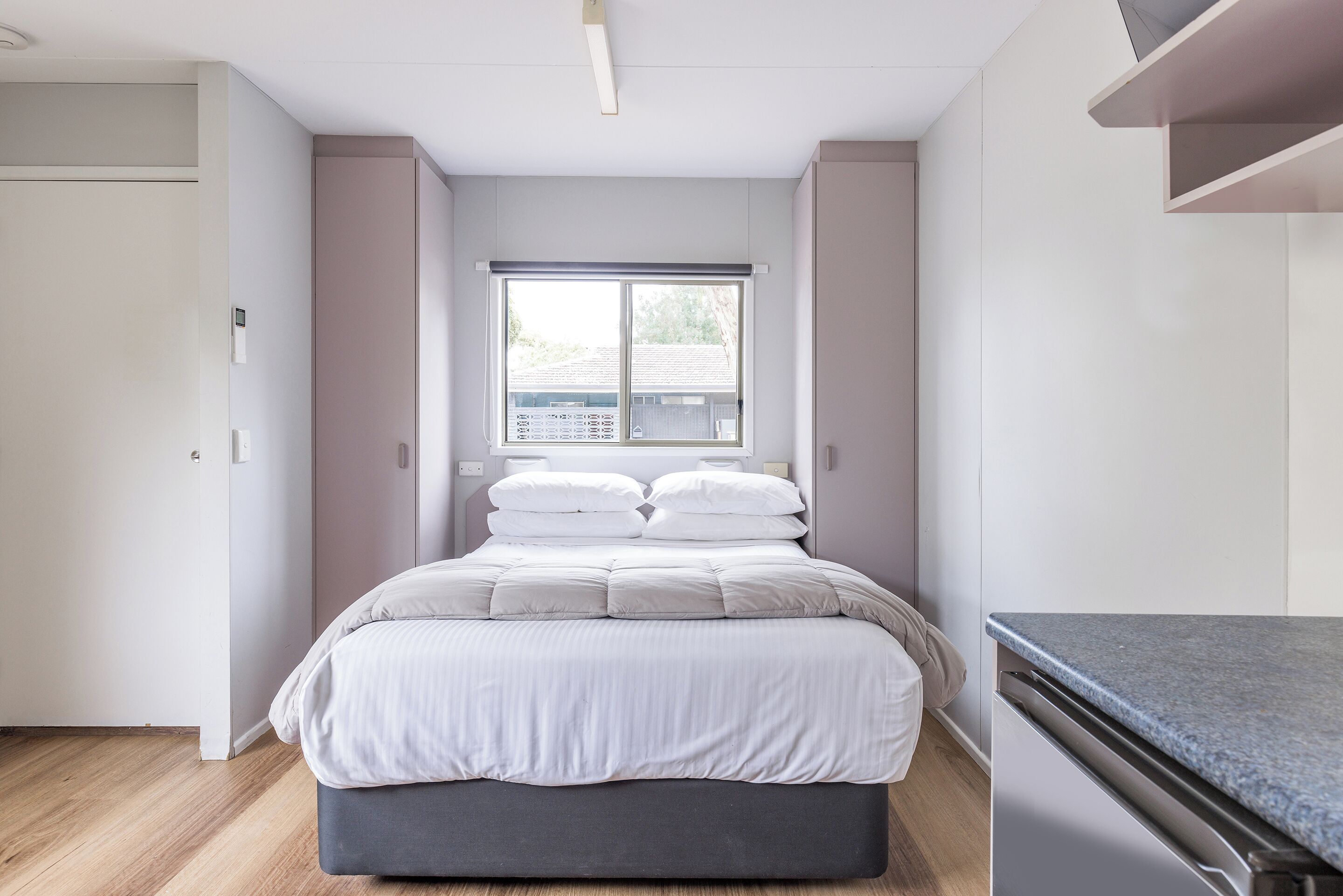 Un dormitorio con cama, ventana y zona de cocina.