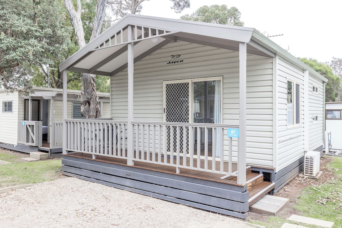 Une maison mobile de plain-pied dotée d’une véranda, d’un porche et d’une petite terrasse.
