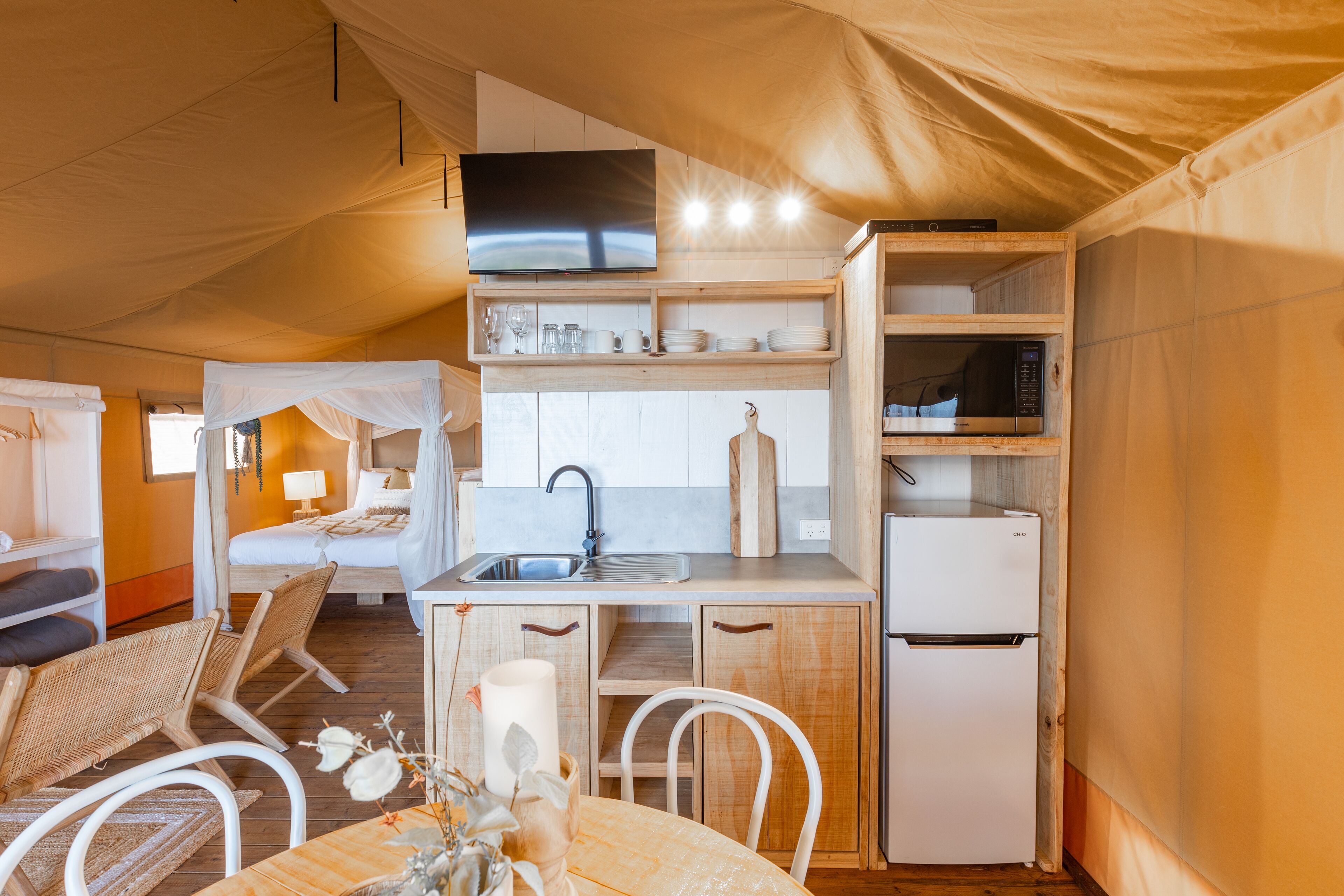 A compact room with a kitchenette, a bed with a canopy, and a dining area.
