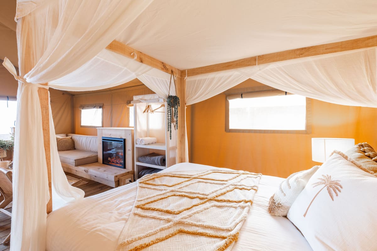 Une chambre à coucher avec un lit, un canapé, une cheminée et une fenêtre.