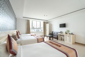 A hotel room with two beds, a desk, a television, and a window with curtains.
