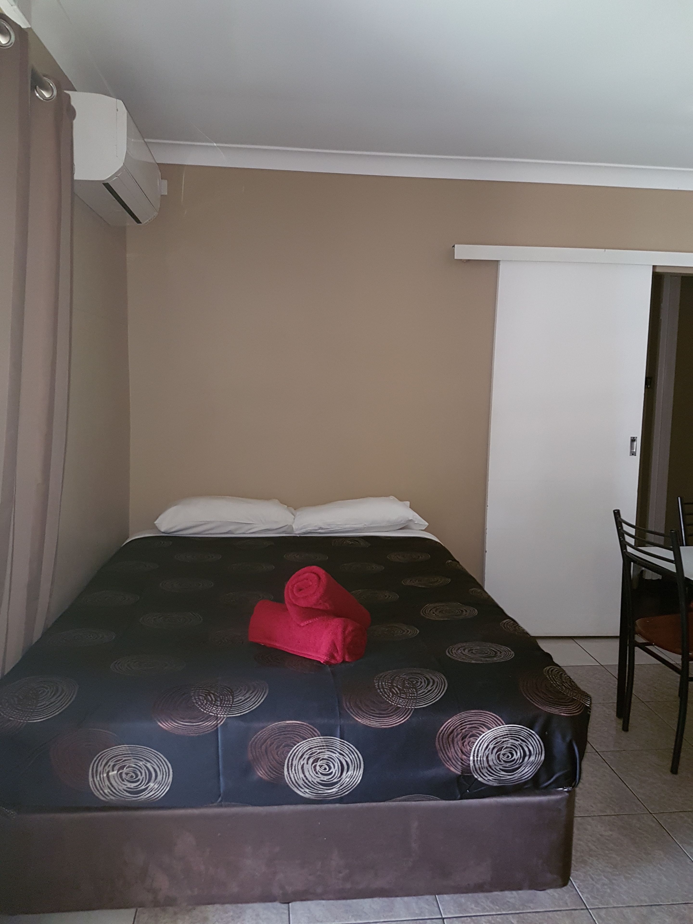 A hotel room with a bed, a chair, and a door.