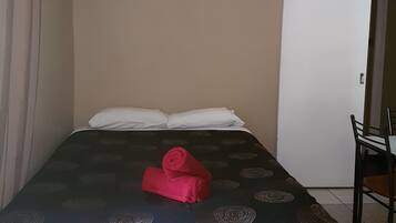 A hotel room with a bed, a chair, and a door.