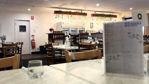A restaurant with tables and chairs, ceiling fans, and hanging plants.