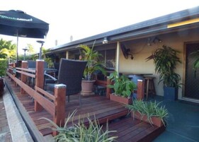 Una terraza exterior con barandas de madera, plantas en macetas y un paraguas negro.