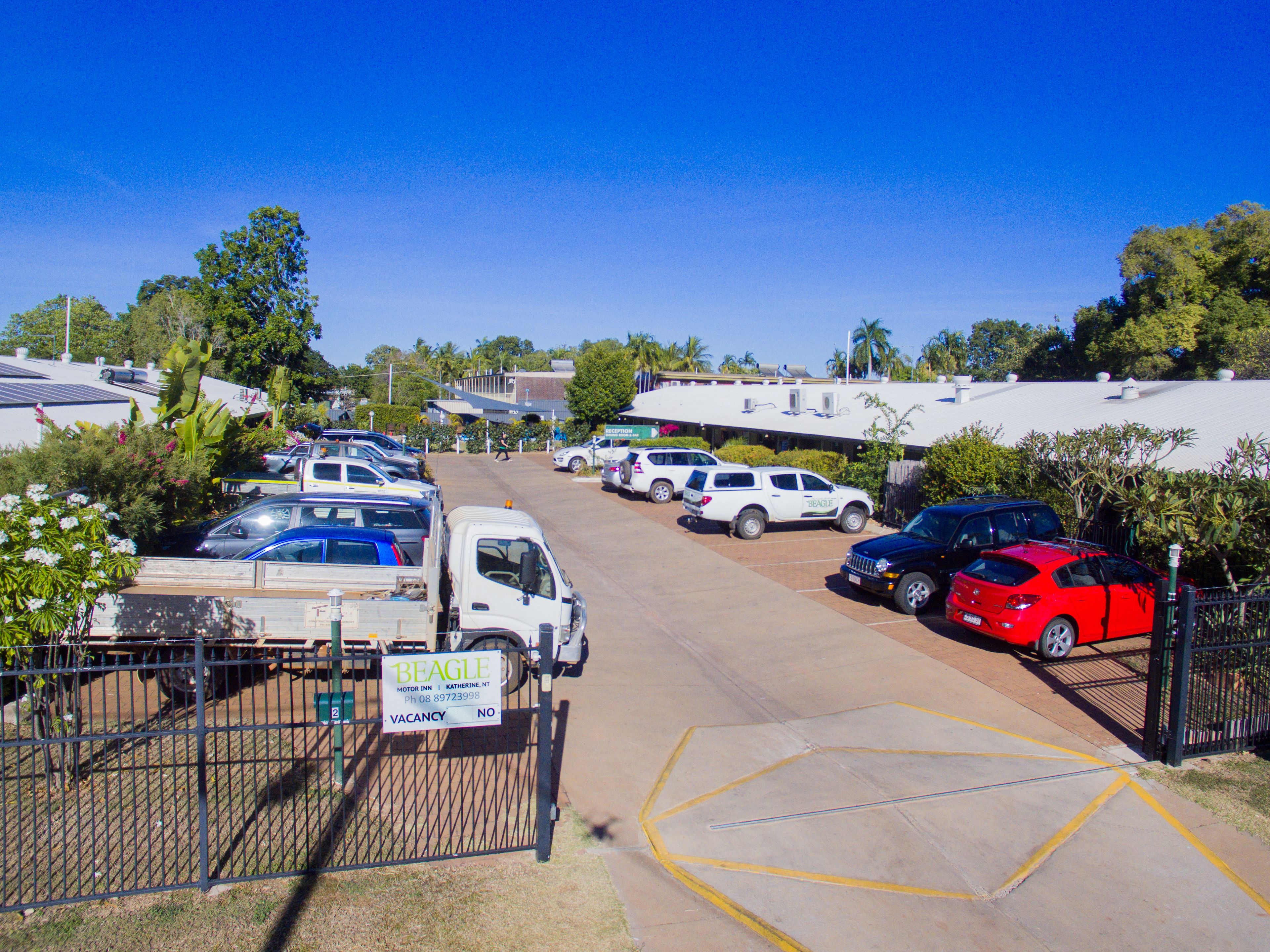 A parking lot with several cars and a sign indicating a vacancy.