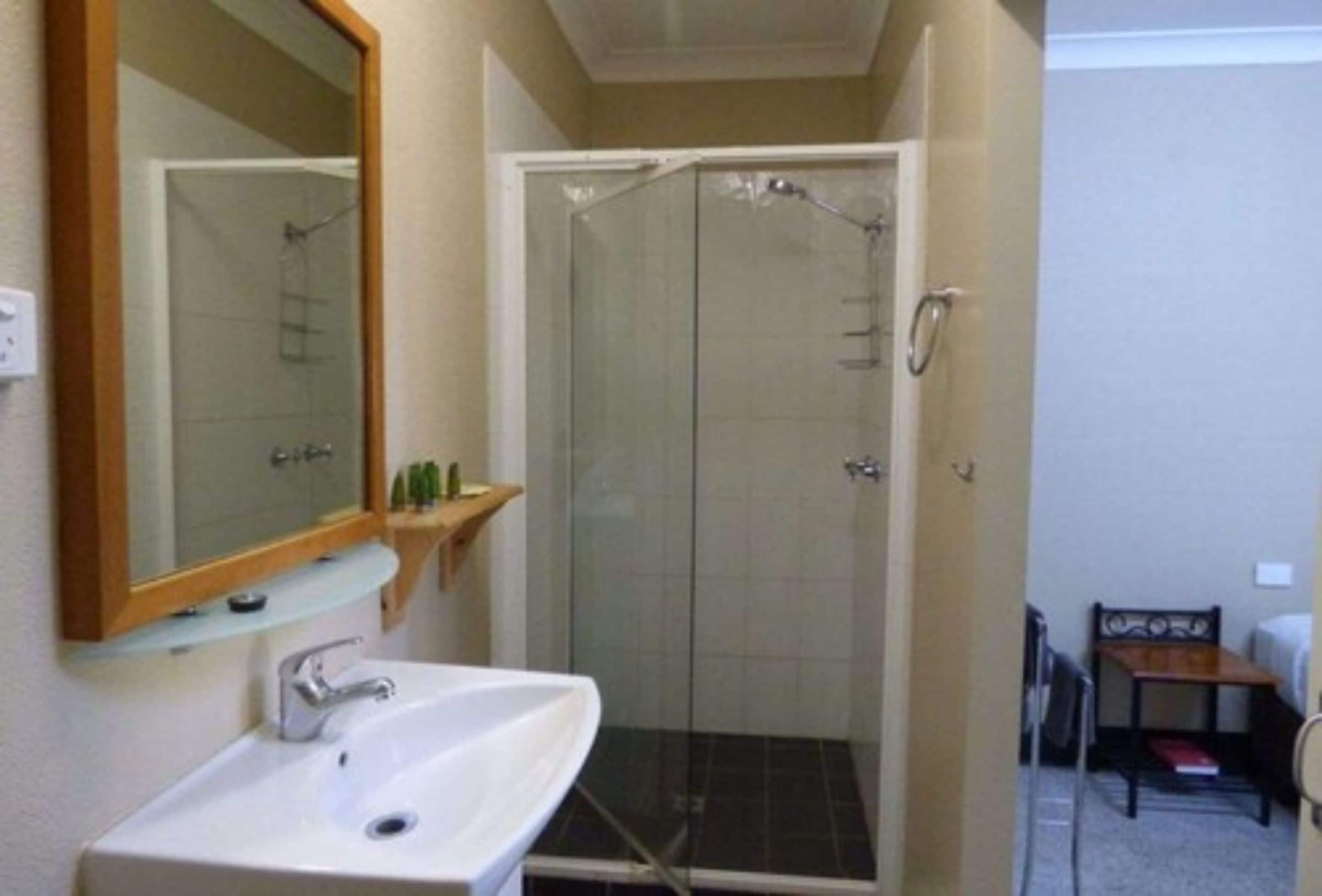 A bathroom with a glass-enclosed shower, a white sink, and a mirror above it.