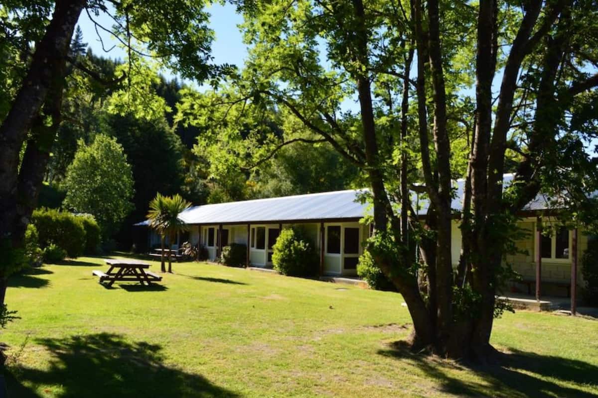 A lodge with a covered patio, surrounded by lush greenery and trees.