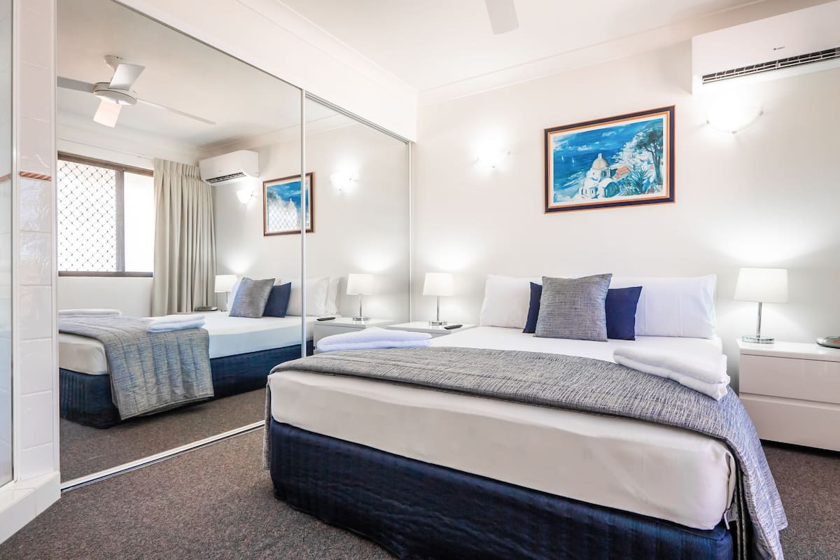 Une chambre d’hôtel avec un grand lit, une table de chevet avec une lampe, un miroir et un tableau au mur.