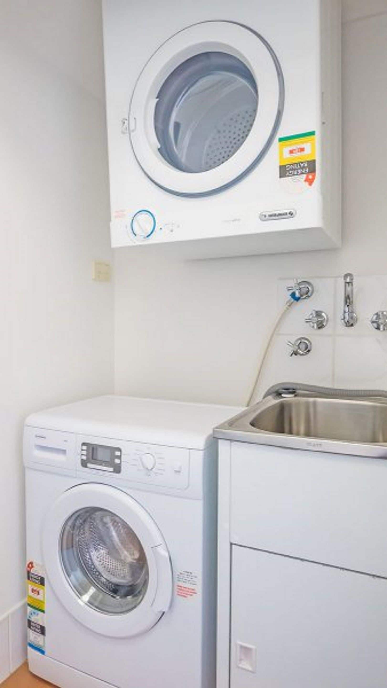 A compact laundry area with a front-loading washing machine and a built-in sink.