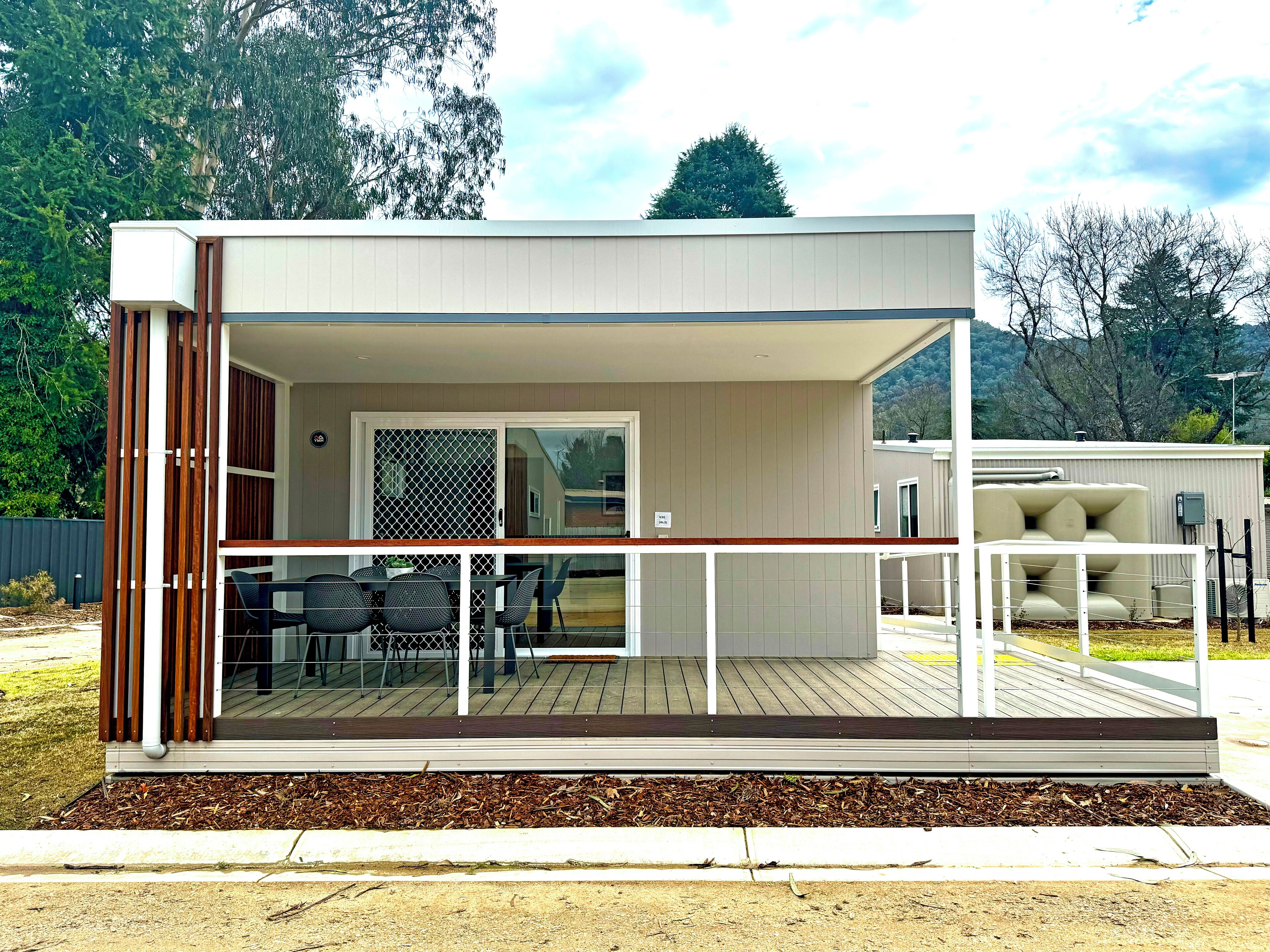 Une maison moderne de plain-pied dotée d’un patio couvert, d’une porte-fenêtre coulissante et d’une petite terrasse.