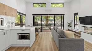 Una cocina moderna con armarios blancos, microondas integrado y un comedor con mesa y sillas.