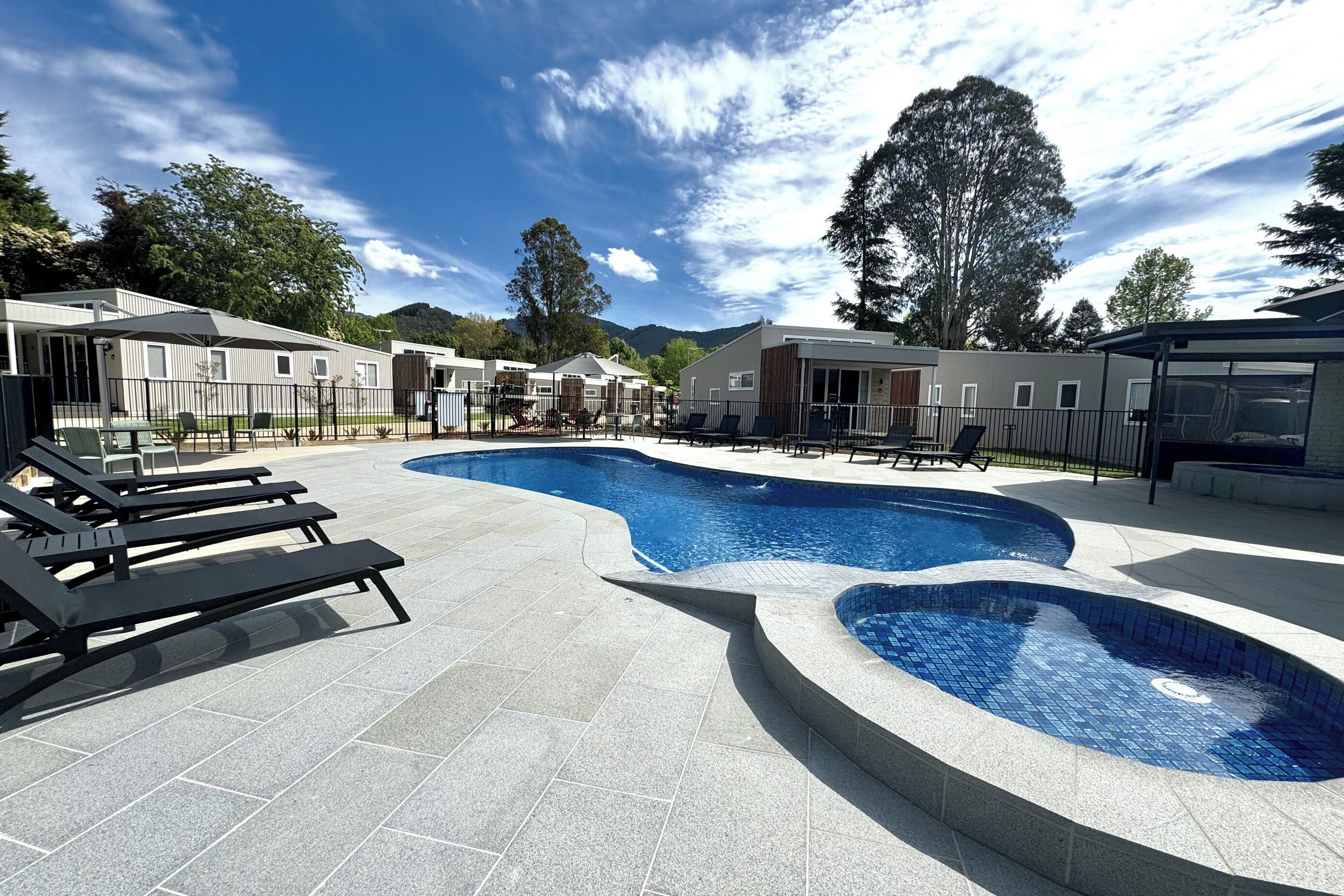 A swimming pool with lounge chairs and a building complex in the background.