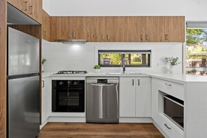 Una cocina moderna con armarios de madera, electrodomésticos de acero inoxidable y un ventanal que proporciona luz natural.