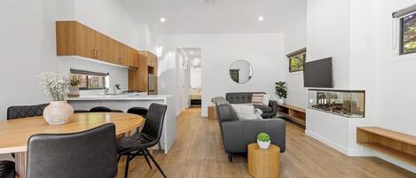 A modern living space with a dining area, a sofa, a TV, and a ceiling fan.