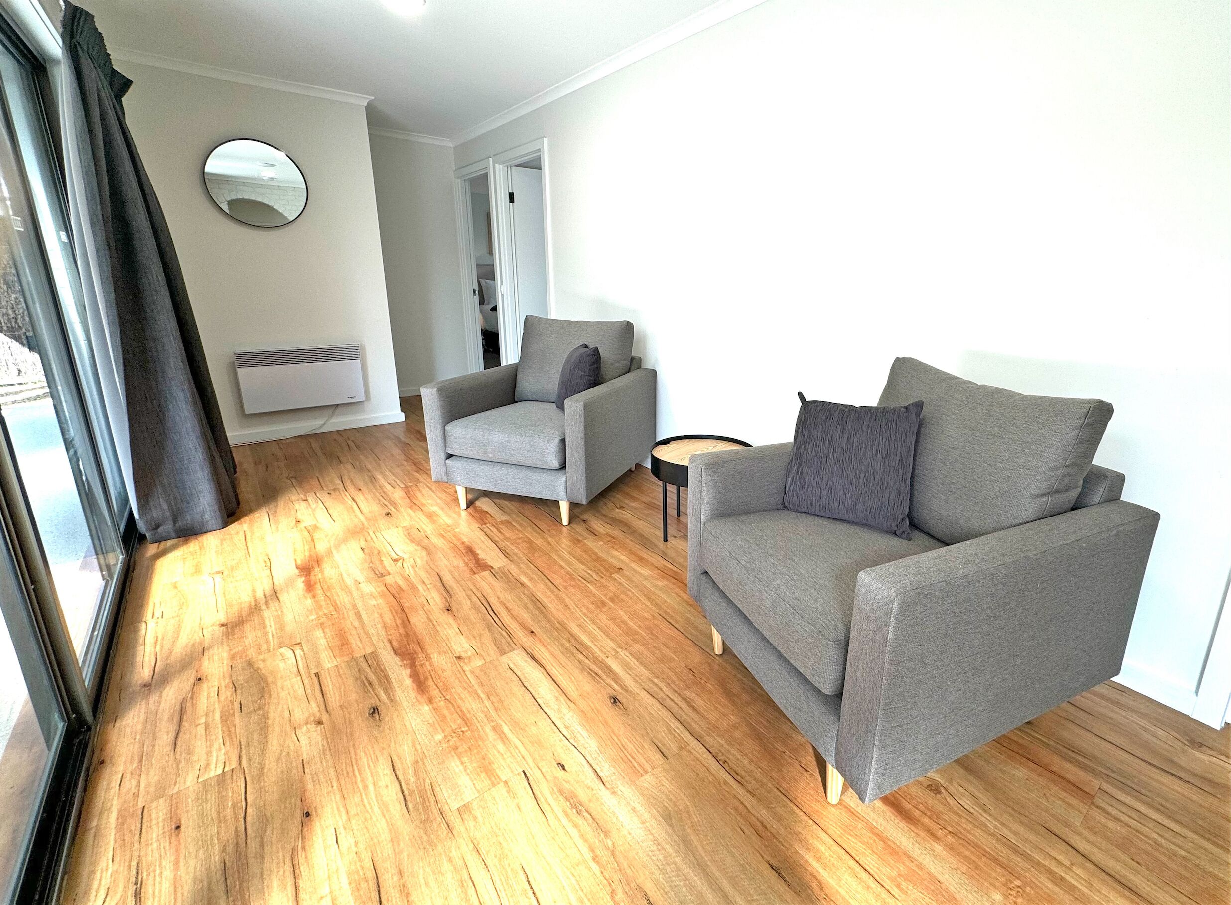 Una sala moderna con un sofá gris, un sillón gris y una mesa de centro redonda.