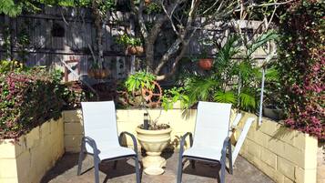 Relax in a serene outdoor space surrounded by lush greenery and a wooden fence.