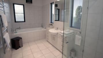 Un baño moderno con bañera, lavamanos y cabina de ducha de vidrio.