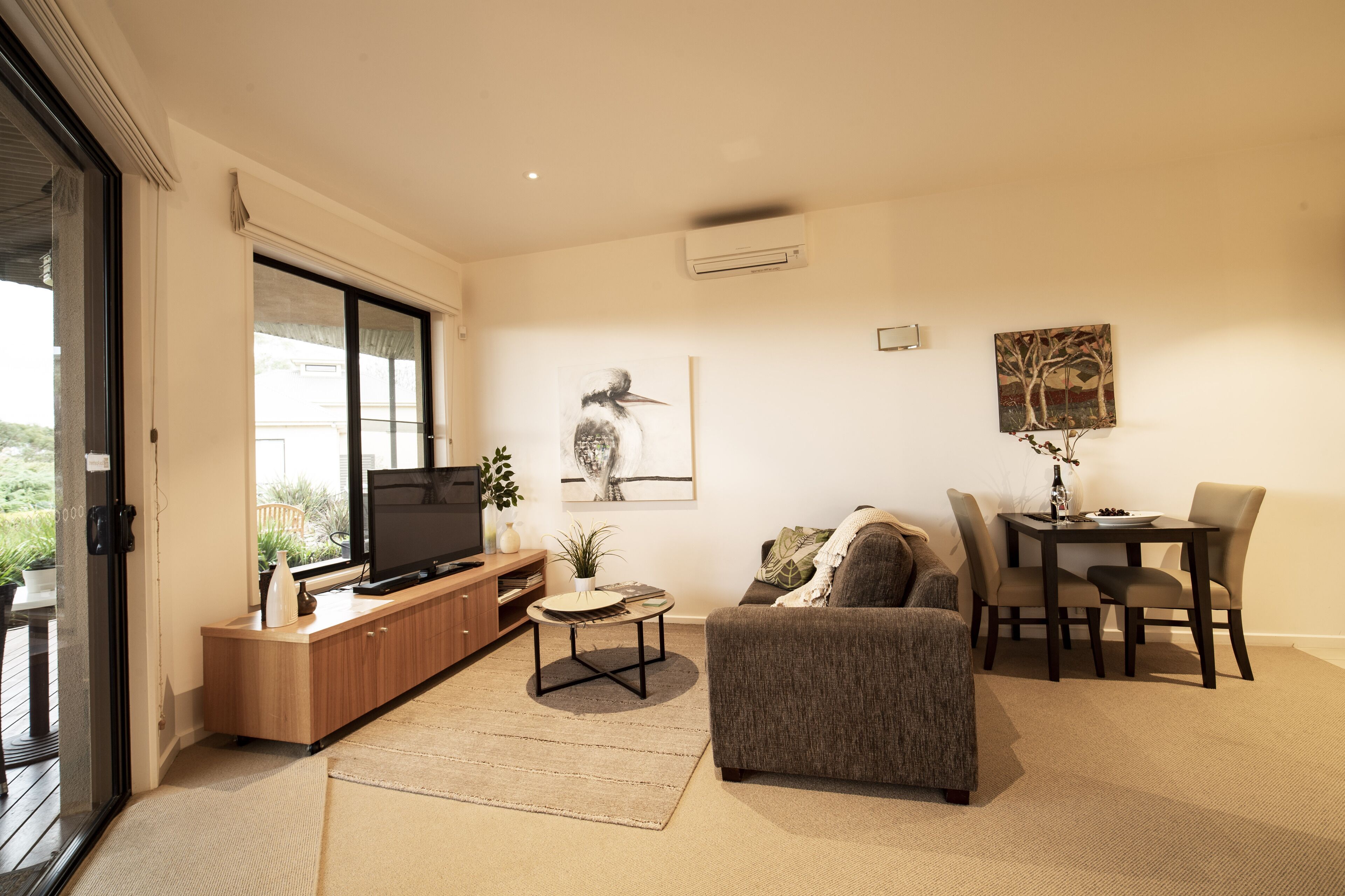 A modern living room with a television, sofa, dining table, and chairs.