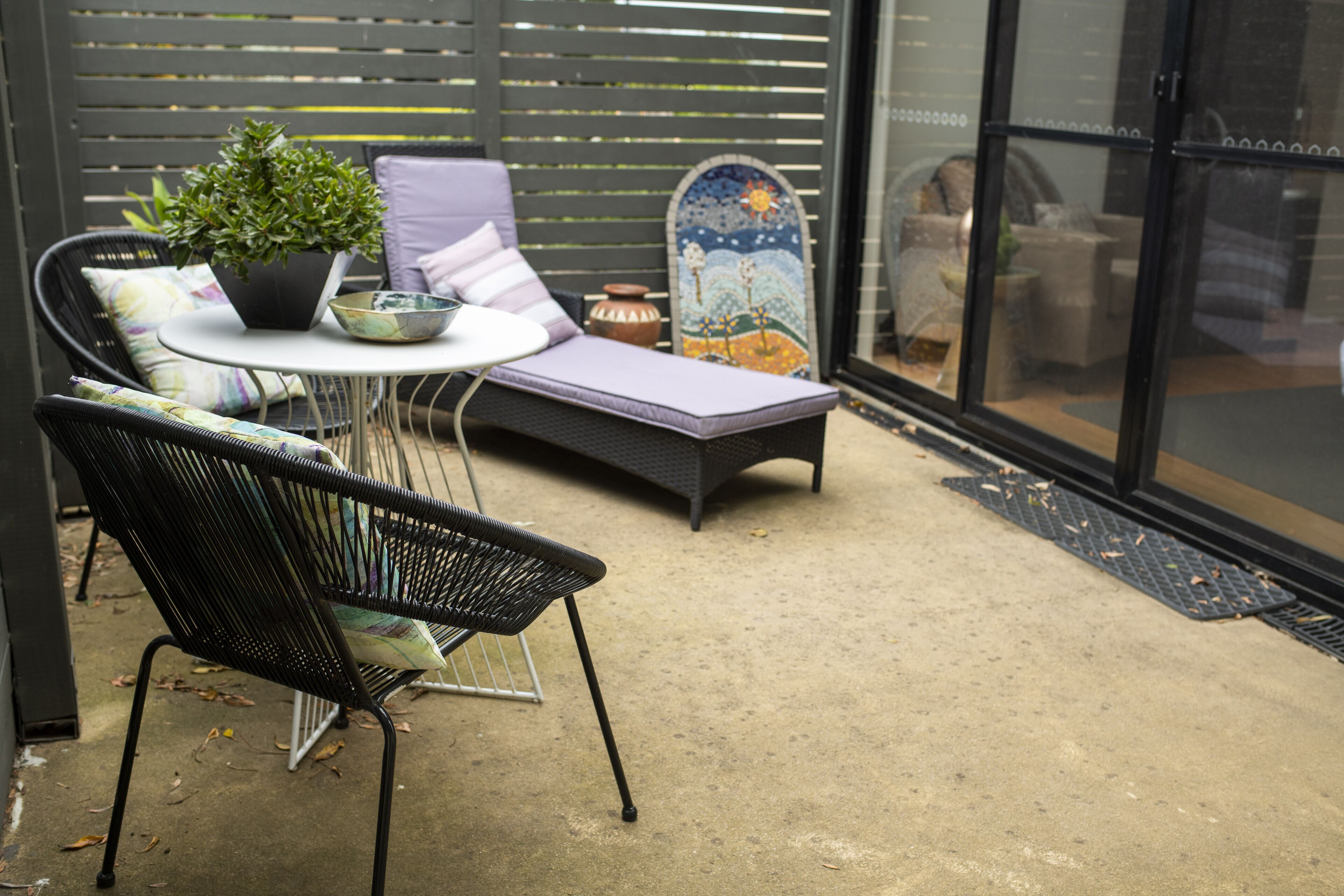 A patio with a lounge chair, a small table, and a potted plant.