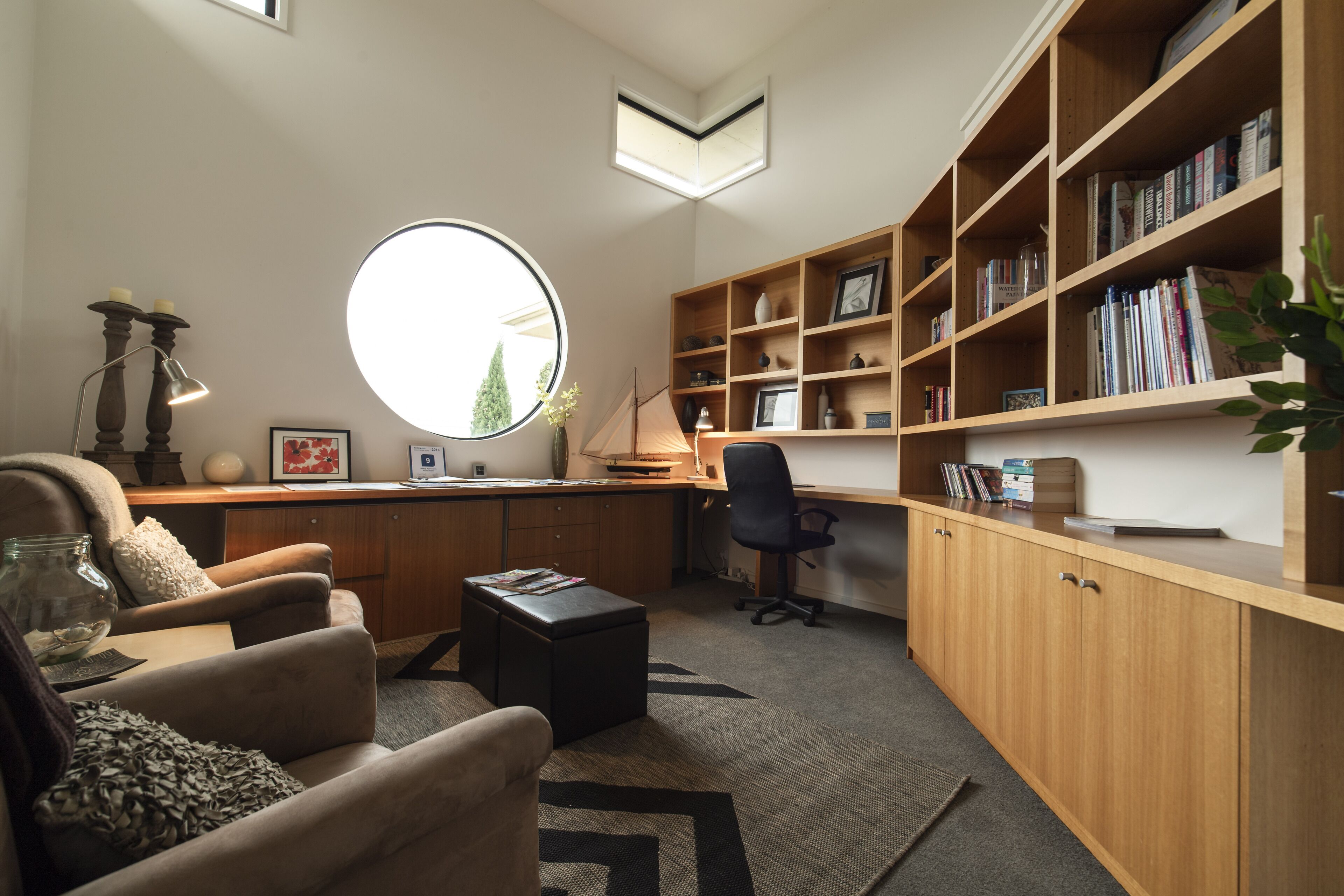 A modern office space with a desk, office chair, and a large bookshelf filled with books and decorative items.