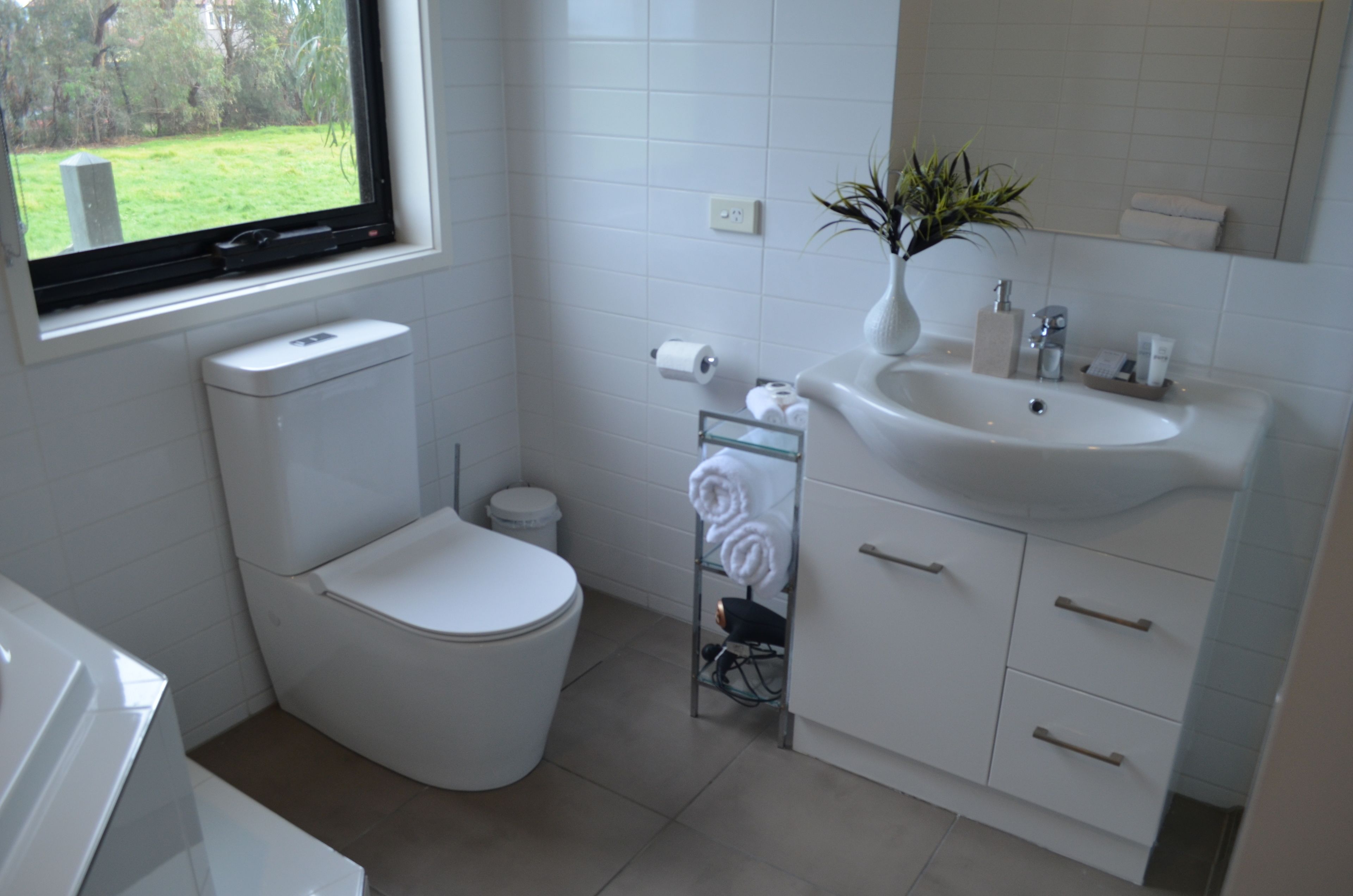 A modern bathroom with a toilet, sink, and window.
