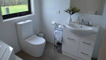 A modern bathroom with a toilet, sink, and window.
