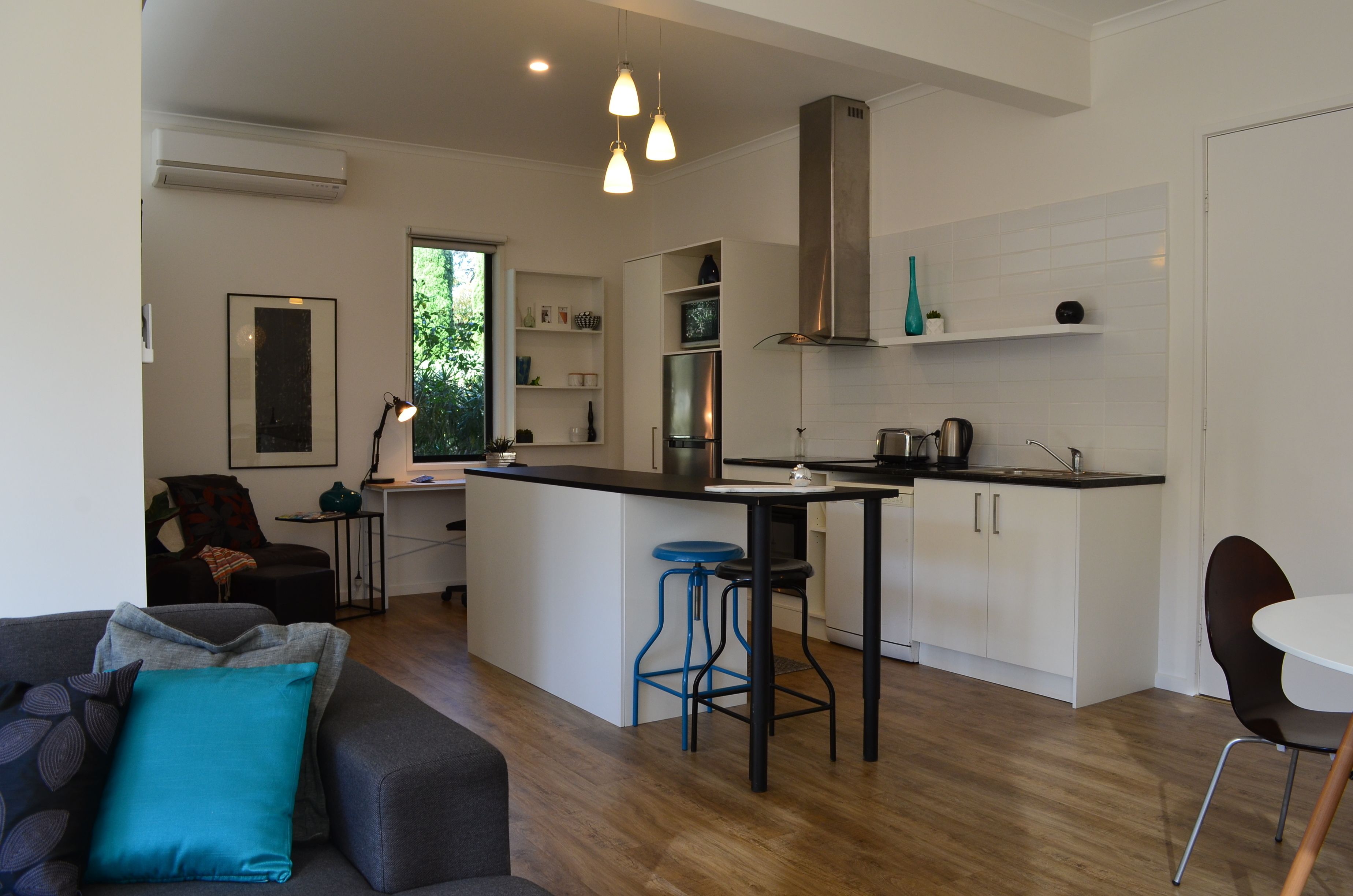 A modern kitchen with white cabinets, a central island, bar stools, and pendant lighting.