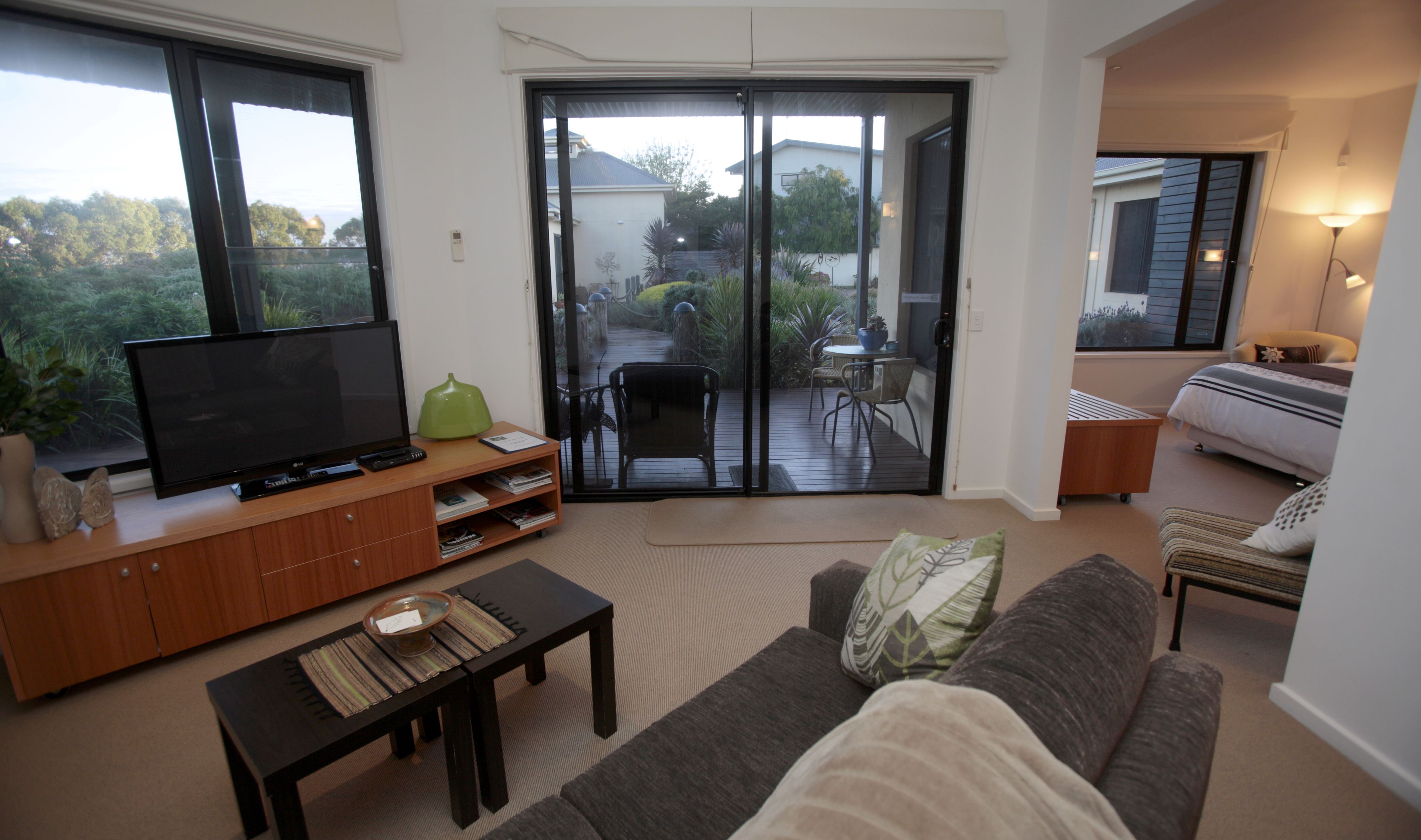 A living room with a TV, sofa, coffee table, and a sliding glass door leading to a patio.